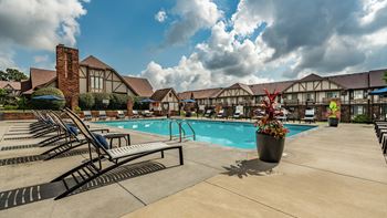 A pool area with sun loungers and a building in the background